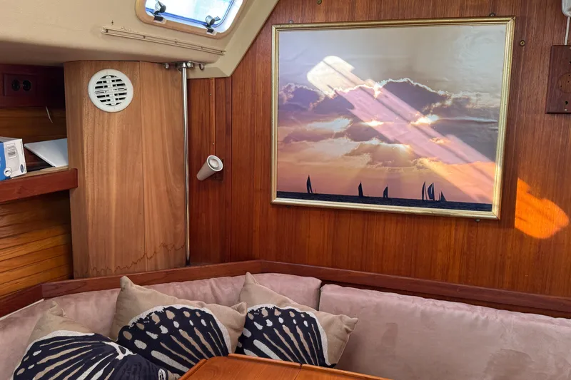 Cozy Catalina 42 yacht interior with sunset painting, cushions, and wooden paneling.