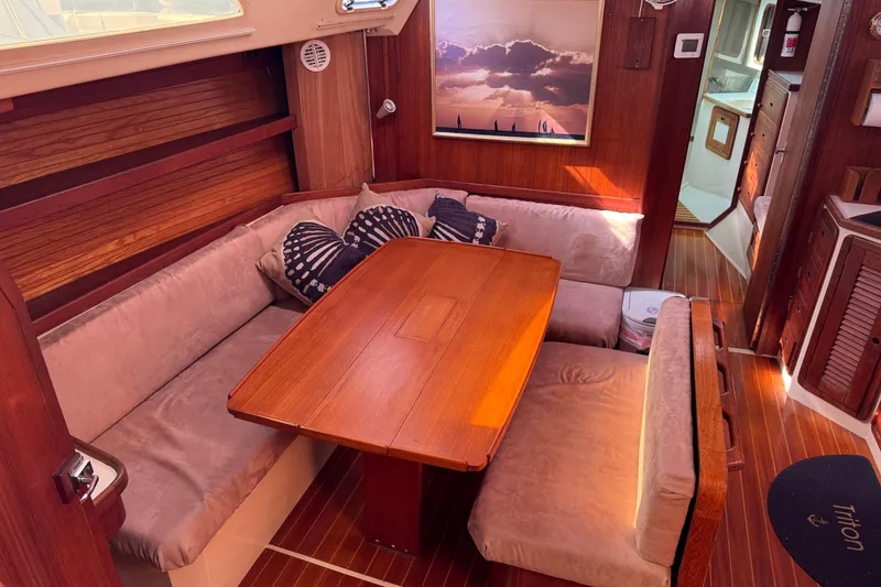 Cozy interior of a 1989 Catalina 42 sailboat with wooden dining area and plush seating.