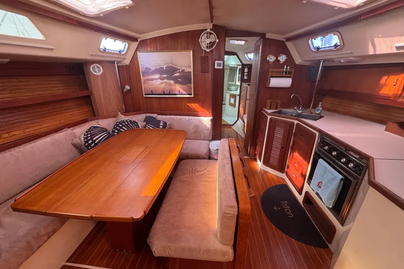 Interior of a 1989 Catalina 42 sailboat with cozy seating and a compact kitchen.