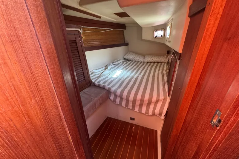 Cozy cabin interior of 1989 Catalina 42 sailboat with striped bedding and wooden accents.