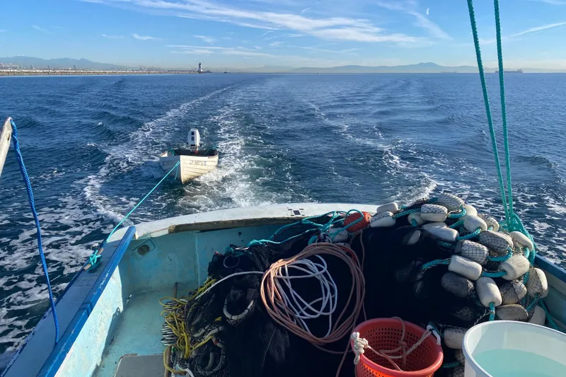Fishing boat Roberts 30 (1977) towing a small dinghy on open water.