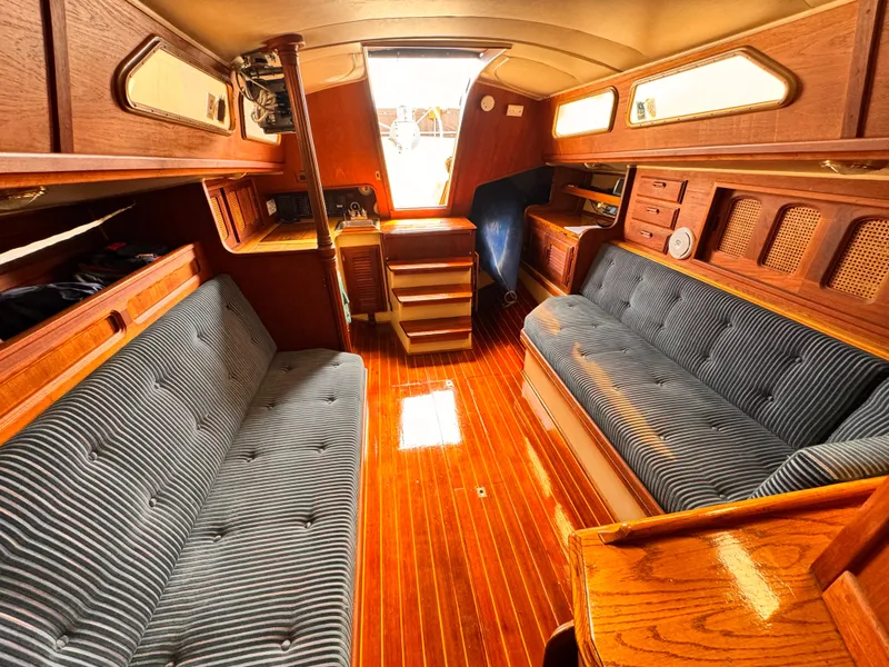 Interior of a 1978 Islander 36 sailboat with wood paneling and striped upholstery.