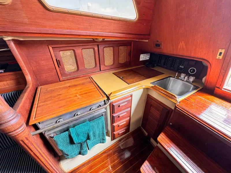 1978 Islander 36 yacht interior with wooden cabinetry, stove, and sink.