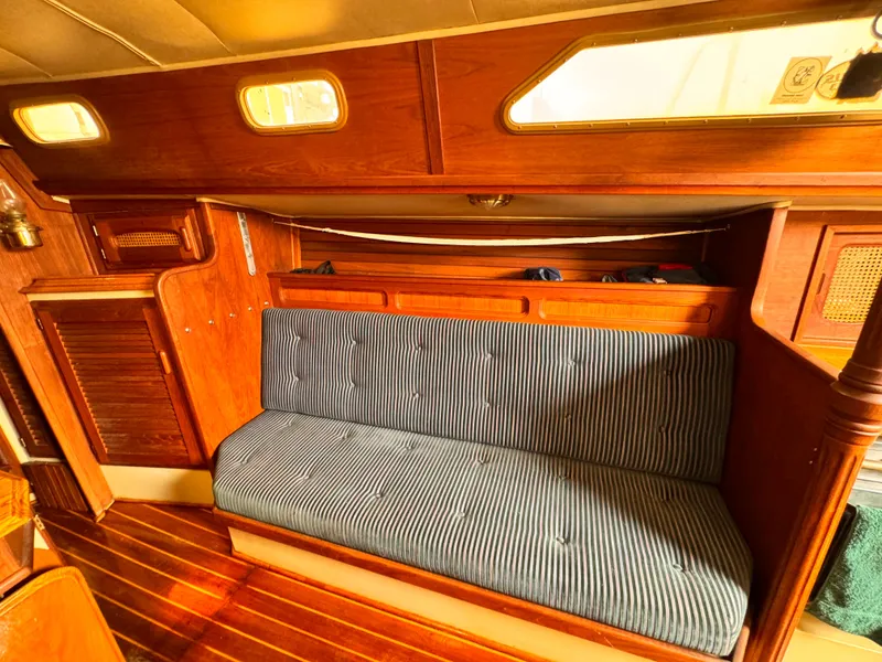 1978 Islander 36 sailboat interior with wooden paneling and striped cushioned seating.