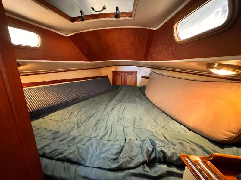 1978 Islander 36 sailboat cabin with cozy bedding and wooden interior.