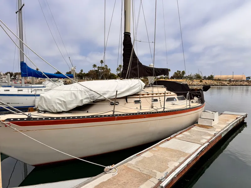 1978 Islander 36 sailboat docked at a marina under a cloudy sky.