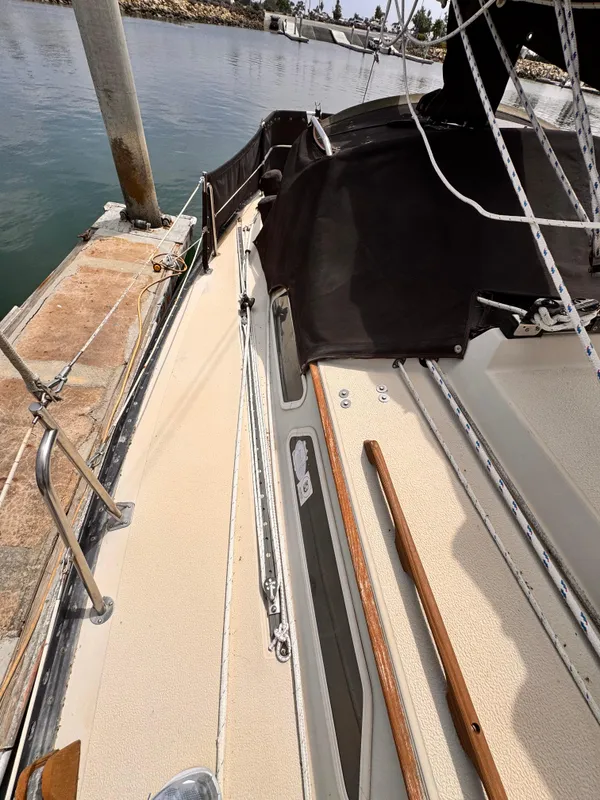 1978 Islander 36 sailboat deck, docked at a marina, featuring wooden handrails and rigging.