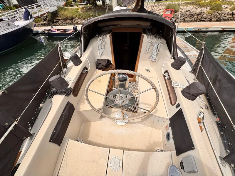 Cockpit of a 1978 Islander 36 sailboat with steering wheel and ropes.