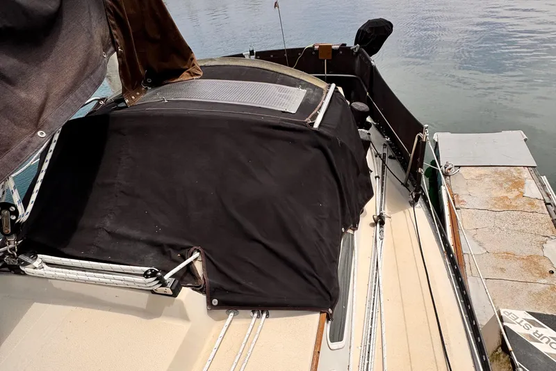 1978 Islander 36 sailboat with black cover docked by the water.