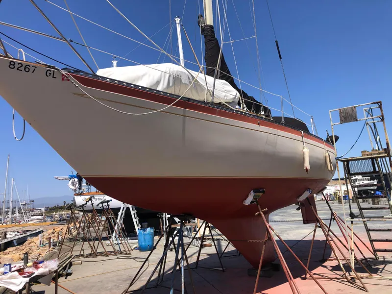 1978 Islander 36 sailboat on dry dock, undergoing maintenance under clear blue sky.