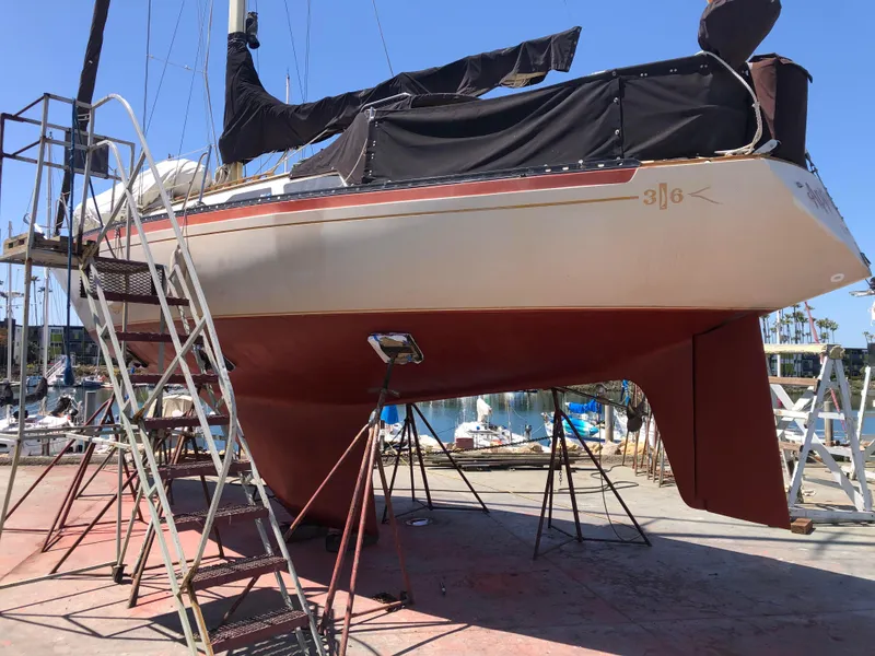 1978 Islander 36 sailboat on dry dock with red hull and black cover.