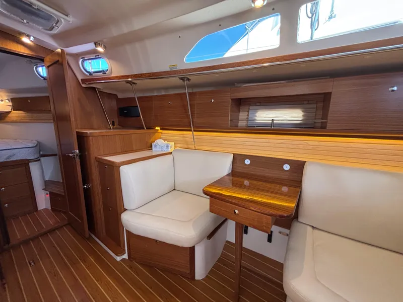 Interior of 2019 Catalina 385 sailboat with wooden furnishings and cozy seating area.