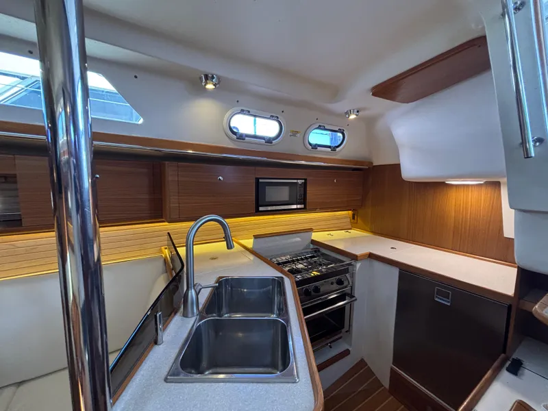 Modern kitchen interior of 2019 Catalina 385 yacht with dual sinks and stainless steel appliances.