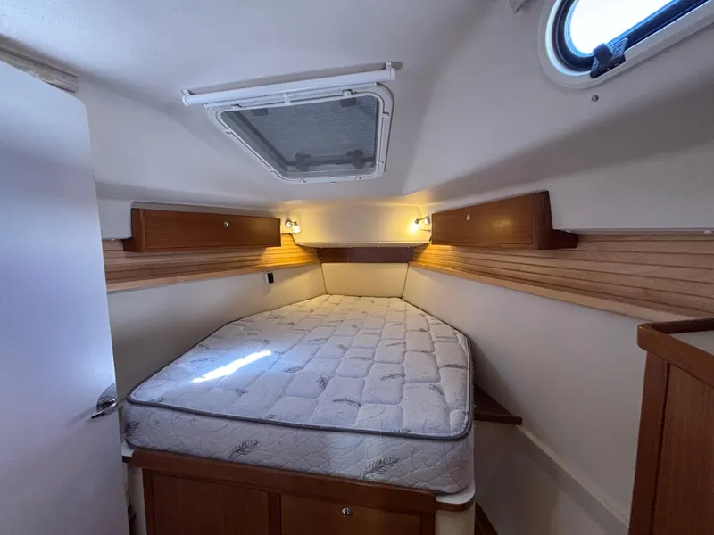 Cozy cabin interior of 2019 Catalina 385 sailboat with bed and wooden accents.