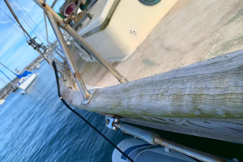 Close-up of 1980 Tayana Pilot House sailboat deck with weathered wood and marina view.