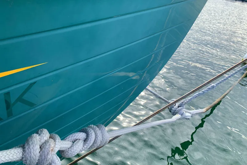Close-up of 1980 Tayana Pilot House boat hull with rope detail on water.