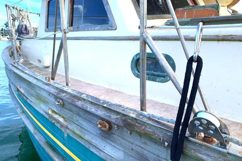 1980 Tayana Pilot House boat with weathered wood and metal railings docked by the water.