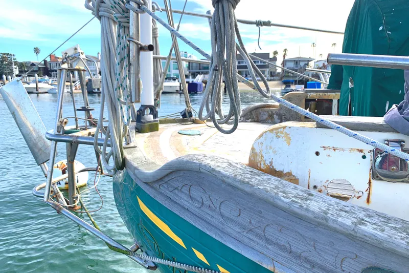 1980 Tayana Pilot House sailboat docked, showcasing weathered wood and nautical ropes.