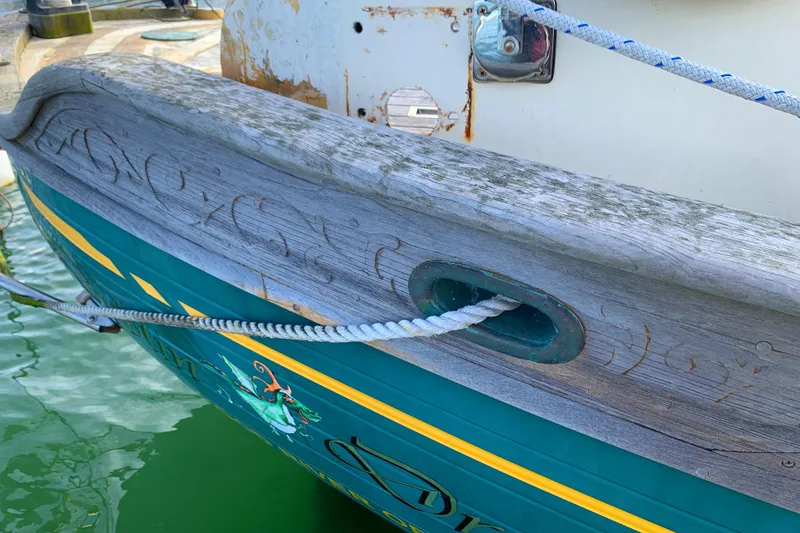 1980 Tayana Pilot House boat with decorative woodwork and rope detail at dock.