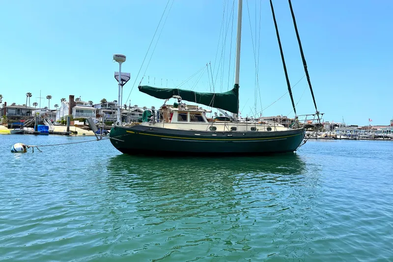 1980 Tayana Pilot House sailboat docked in a sunny marina.