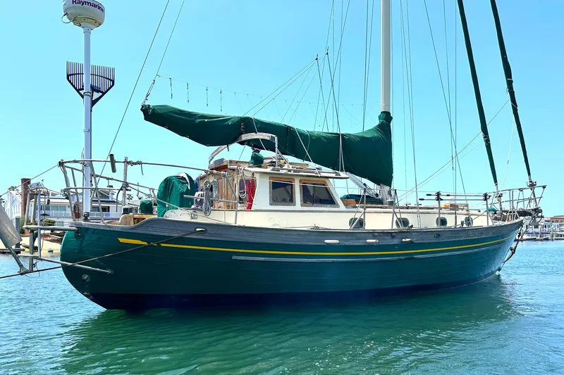 1980 Tayana Pilot House sailboat docked in a marina under clear blue skies.