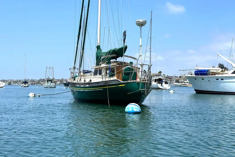 1980 Tayana Pilot House sailboat moored in a calm harbor under a clear blue sky.