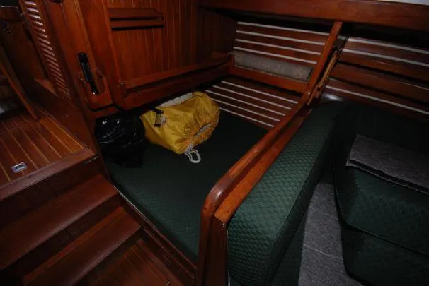 1980 Tayana Pilot House interior with wooden finish and green cushions.