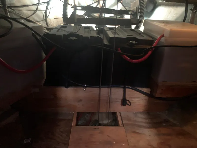 Battery compartment of a 1980 Tayana Pilot House sailboat with wiring and wooden supports.