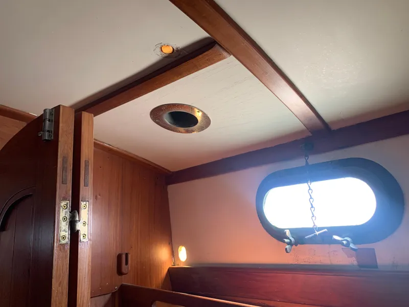 1980 Tayana Pilot House interior with wooden paneling and porthole window.