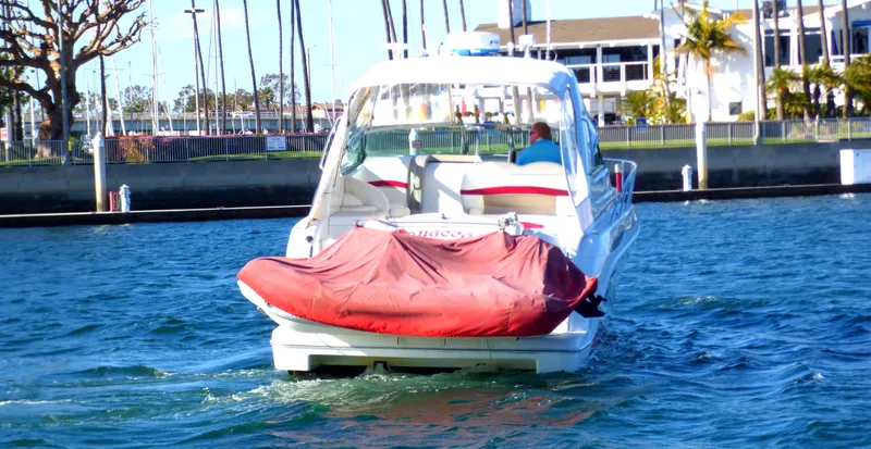 2003 Formula 37 PC boat cruising in marina with red cover on rear.
