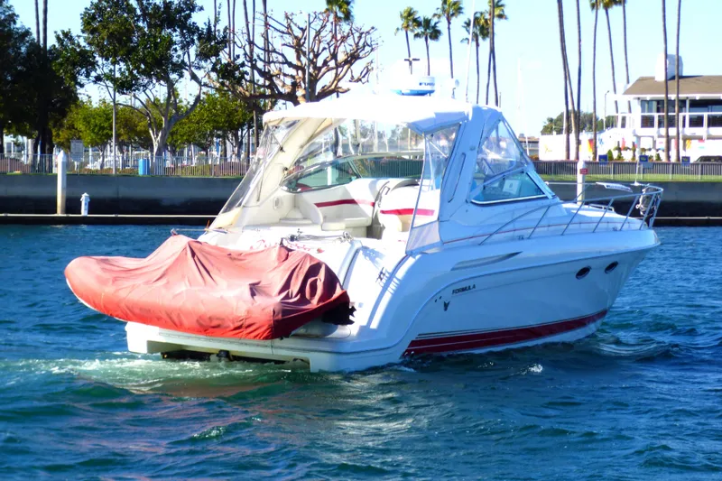 2003 Formula 37 Performance Cruiser on water, with red cover, palm trees in background.