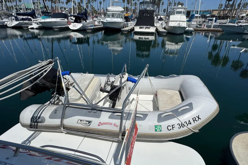 Inflatable boat docked at marina, surrounded by various yachts and clear blue water.