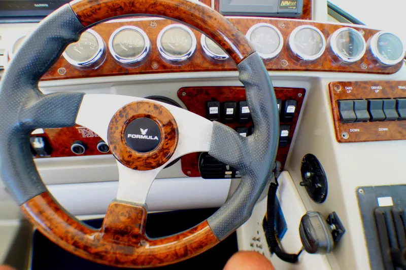 Steering wheel and dashboard of a 2003 Formula 37 PC boat, featuring wood accents and gauges.