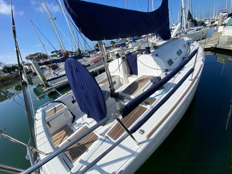 2004 Beneteau 36.7 sailboat docked in a marina, featuring blue covers and wooden deck.