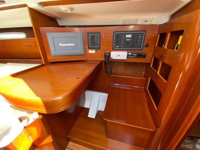 2004 Beneteau 36.7 navigation station with Raymarine electronics and wooden cabinetry.