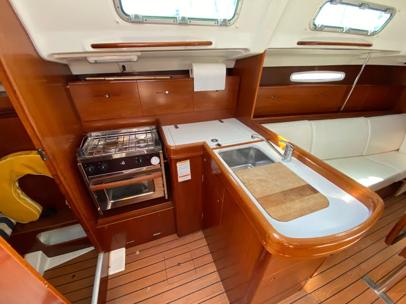 2004 Beneteau 36.7 yacht interior with kitchen, stove, sink, and seating area.
