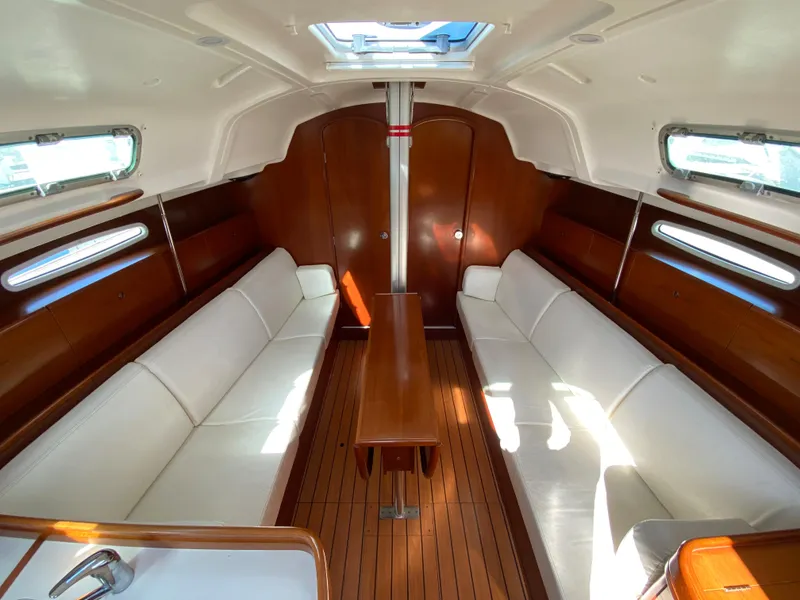 Interior of 2004 Beneteau 36.7 sailboat with white seating and wooden finishes.
