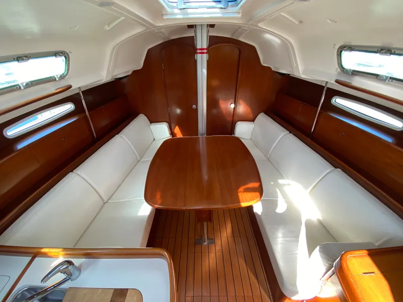 Interior of 2004 Beneteau 36.7 sailboat with wooden table and white seating.
