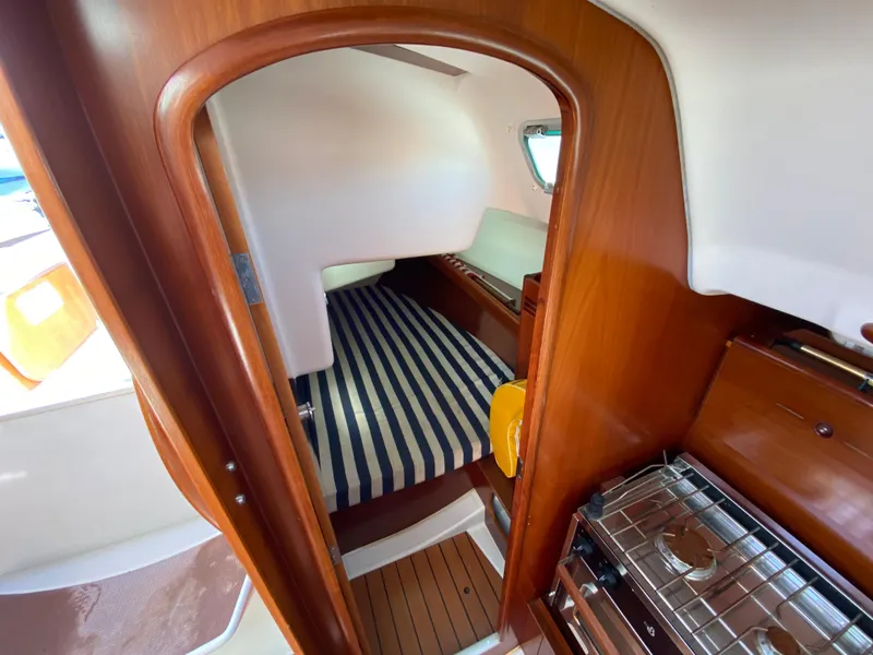Interior cabin of 2004 Beneteau 36.7 sailboat with striped bedding and wooden finishes.