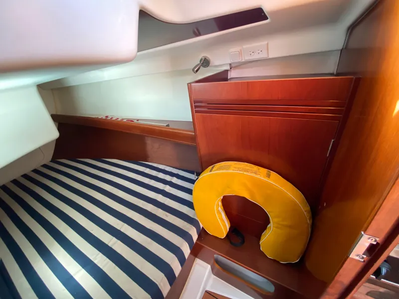 Interior cabin of 2004 Beneteau 36.7 sailboat with striped bedding and life preserver.