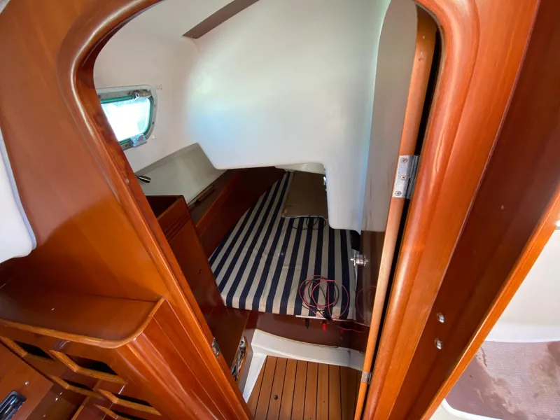 2004 Beneteau 36.7 cabin interior with striped bedding and wooden finish.