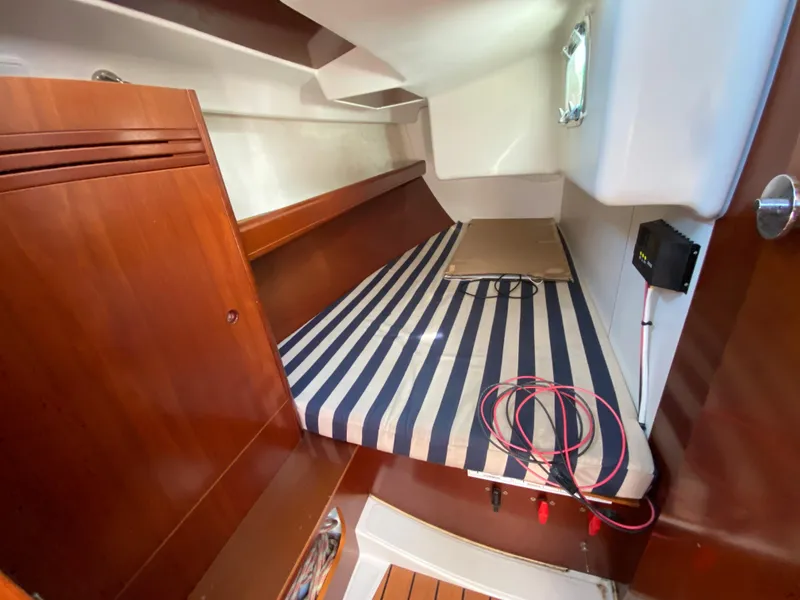 Interior cabin of 2004 Beneteau 36.7 sailboat with striped bedding and wooden cabinetry.