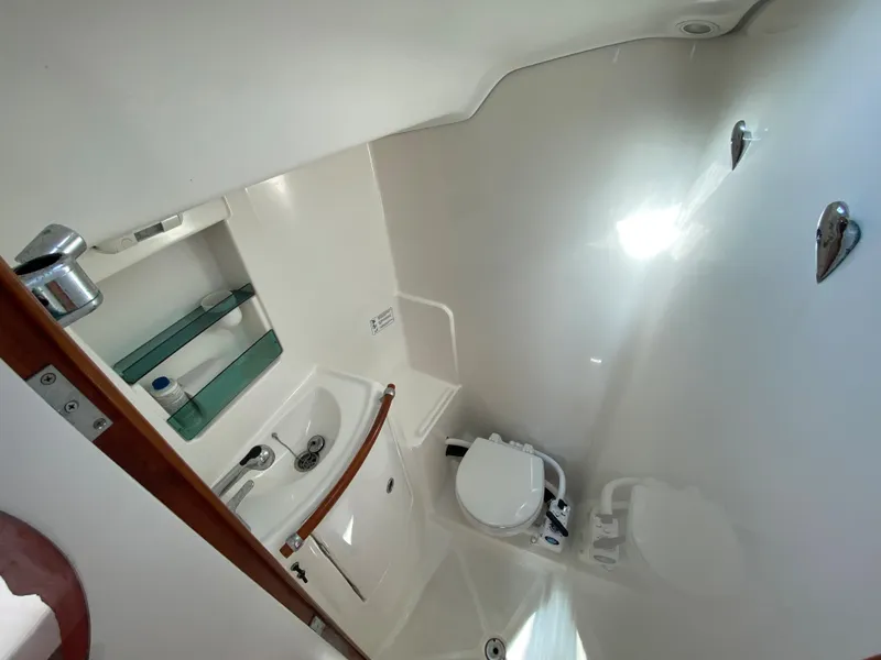 2004 Beneteau 36.7 sailboat bathroom with sink, toilet, and storage shelves.