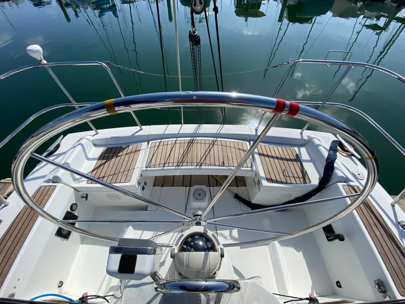 2004 Beneteau 36.7 sailboat cockpit with large steering wheel and teak flooring.