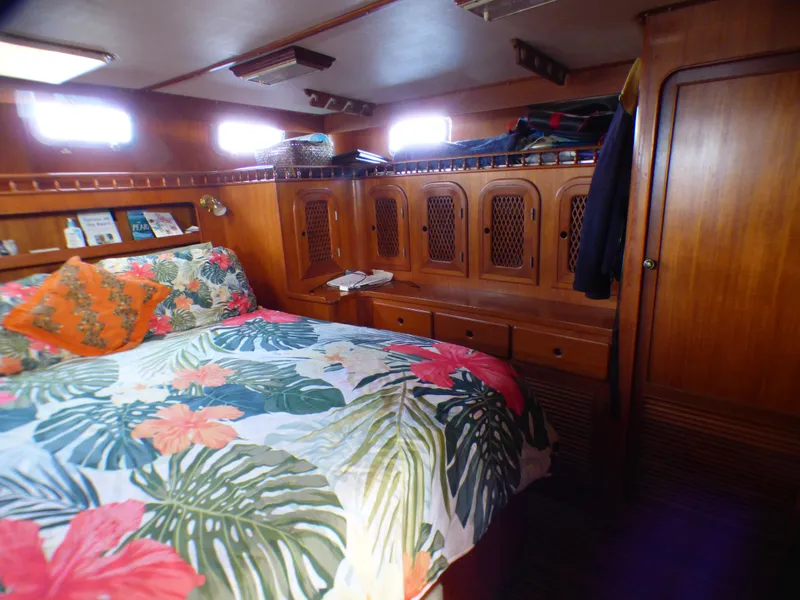 Cozy cabin interior of 1984 Spindrift 39 ft. yacht with floral bedding and wooden cabinetry.