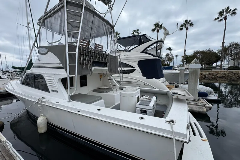 1993 Blackfin Sportfisher boat docked at marina with overcast sky and palm trees.