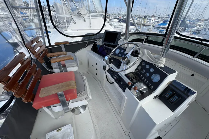 1993 Blackfin Sportfisher helm with steering wheel, controls, and seating in a marina setting.