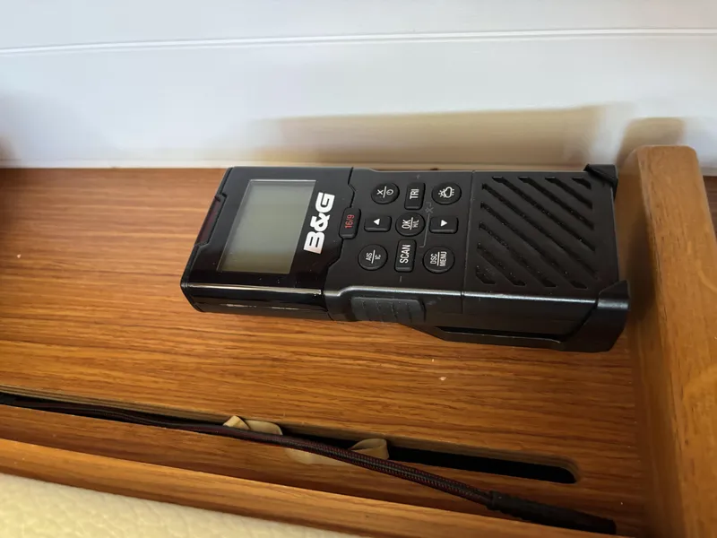 Handheld B&G marine radio on Bavaria Cruiser 34, 2020 model, wooden surface.