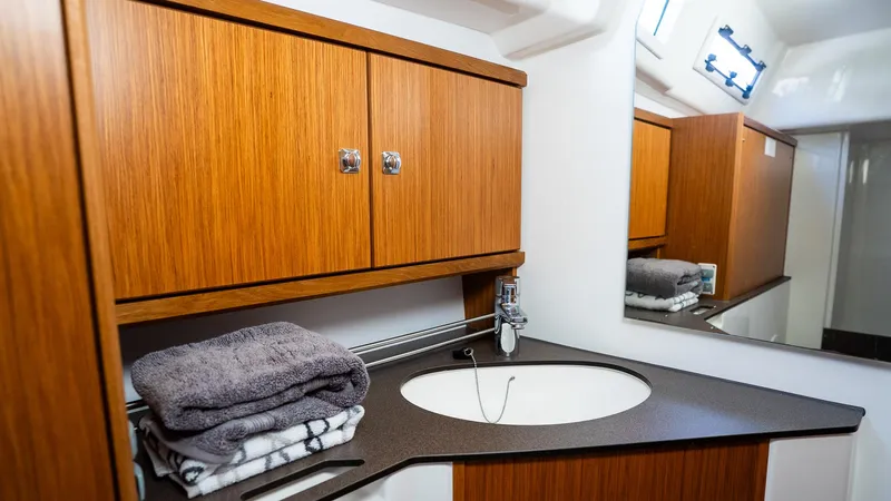 Modern bathroom in 2020 Bavaria Cruiser 34 yacht with wooden cabinets and sleek sink design.
