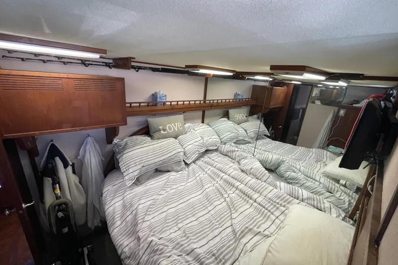 1975 Uniflite Sport Fisher 42 cabin with cozy striped bedding and wooden accents.
